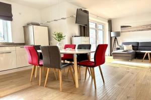 a dining room table with red chairs in a living room at Ferienwohnung Sturmeck, Fehmarn-Orth in Orth