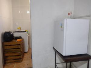 a kitchen with a white refrigerator and a wooden table at Aconchego Green - Centro de Rio das Ostras in Rio das Ostras