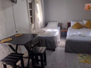 a room with two beds and a desk and a table at Aconchego Green - Centro de Rio das Ostras in Rio das Ostras