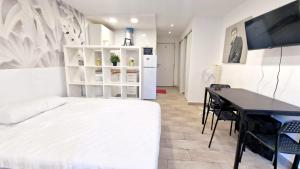 una camera da letto con un letto bianco e una scrivania di Apartamentos Gamonal Costa del Sol a Málaga Altre 14 foto