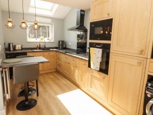 una cocina con armarios de madera y electrodomésticos negros en 10 Keekle Terrace, en Cleator Moor