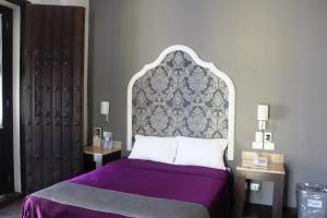 a bedroom with a bed with a purple bedspread at Hotel Gala in Puebla