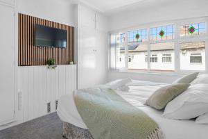 a white bedroom with a bed and a flat screen tv at Contractor Stays, Newly Renovated, Free Parking, Sleep 7 in Wallasey