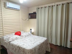 a bedroom with a bed with a red hat on it at CHALÉ ALPINO RAIZ TODO MOBILIADO COM 2 QUARTOS COZINHA SALA BANHEIRO NATUREZA 2 KM centro de Canela rs in Canela