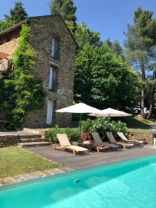 a group of chairs and umbrellas next to a pool at La Bastide en Cévennes in Saint-Hilaire-de-Lavit