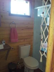 Un baño con inodoro y una toalla rosa. en Ilha das Peças "Pousada do Beto", 
