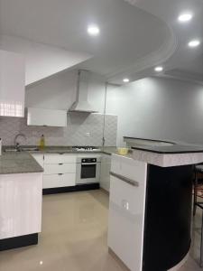 a kitchen with white cabinets and a black counter top at Jinene logement in Yasmine