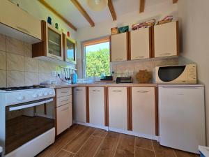 a kitchen with white cabinets and a microwave at Domek pod Czulnią in Uherce Mineralne