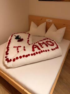 een wit bed met rode rozen erop bij Sirona Stay - Private Spa Retreat with garden, garage and Bolzano-Card in San Genesio Atesino +7 foto's