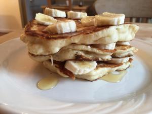 a stack of pancakes with bananas on a plate at Lovat House in Crieff