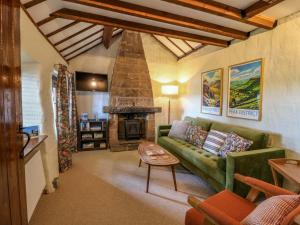 ein Wohnzimmer mit einer grünen Couch und einem Kamin in der Unterkunft Chimney Cottage in Matlock