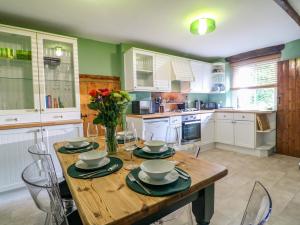 eine Küche mit einem Holztisch mit einer Vase mit Blumen darauf in der Unterkunft Chimney Cottage in Matlock