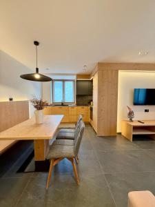Una cocina con una gran mesa y sillas de madera. en Appartamento Rododendro, en Andalo