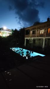 a swimming pool in front of a building at night at GNG Guest House in Telavi