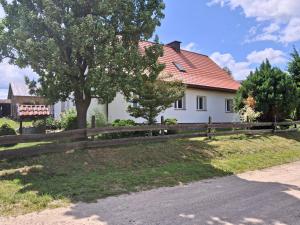 a fence in front of a white house at domek w pobliżu jeziora in Czarnówka