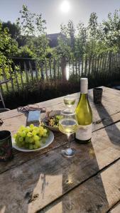 a bottle of wine and a plate of grapes on a wooden table at Vakantiewoning De Specht in Diksmuide