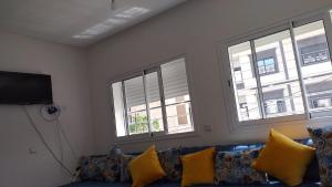a living room with a blue couch and three windows at Appartement de luxe à Saidia in Saïdia