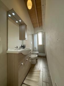 a bathroom with a sink and a toilet and a mirror at Casa vacanze indipendente in Follonica +4 photos