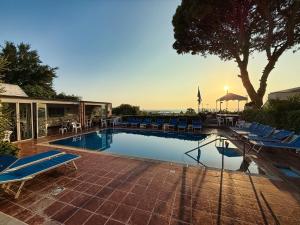 uma piscina com cadeiras azuis e uma casa em Hotel Villa Mena em Ischia