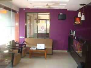 a living room with purple walls and a couch and a table at Hotel Yogiraj in Shirdi