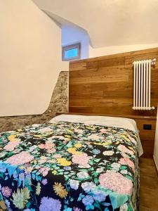 a bedroom with a bed with a floral blanket at BnB Tana del Gufo in Abbadia Lariana