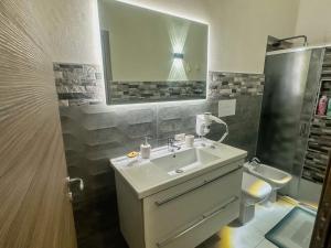 a bathroom with a sink and a toilet and a mirror at Casa Iraci La Nostra Sicilia in Trapani