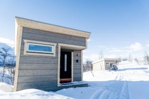 ein kleines Haus im Schnee mit offener Tür in der Unterkunft Enoks i Láddjujávri in Nikkaluokta