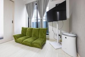 a green chair in a living room with a flat screen tv at Villetta Imari Ekimae III Room 102 - Vacation STAY 19027 in Imari