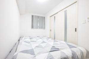 a white bedroom with a bed with a black and white comforter at Villetta Imari Ekimae III Room 102 - Vacation STAY 19027 in Imari