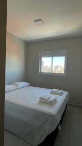 a bedroom with a bed with white sheets and a window at Apartamento completo – perto do centro de Bauru in Bauru