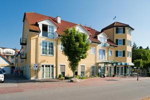 ein großes gelbes Gebäude mit einem Baum davor in der Unterkunft Strandhotel Seestern in Baabe