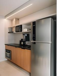 a kitchen with a stainless steel refrigerator and wooden cabinets at Novinho, Central e c/ Garagem! in Pelotas
