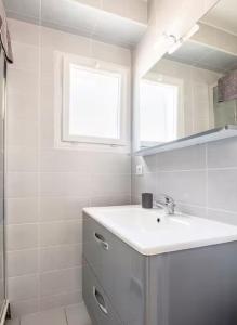 ein weißes Badezimmer mit Waschbecken und Spiegel in der Unterkunft Maison rénové au cœur de Blaye in Blaye