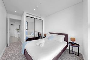 a bedroom with a large white bed and a mirror at Beach Front 2BR Meriton Sunrise & Ocean Views in Gold Coast +12 photos