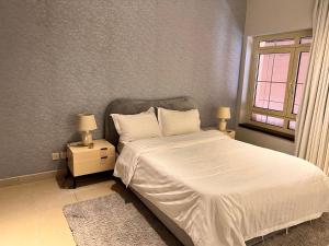 a bedroom with a white bed with two night stands at ليالينا فيو Layali View Family and Business 3 bed rooms 13 in King Abdullah Economic City +39 photos