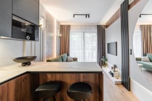 a kitchen with two stools at a counter with a living room at Rogowo Shellter Apartament Premium przy plaży in Rogowo