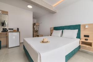 a bedroom with a large white bed with a hat on it at Hotel Sarikas in Polychrono
