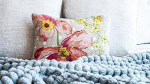 a pillow sitting on a couch with a blue crochet blanket at The Bosun Locker at Seahorse Rentals in Jacksonville Beach