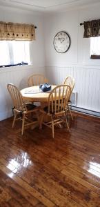 Una mesa de comedor con sillas y un reloj en la pared. en Hatchet Harbour Cottage, en Herring Neck