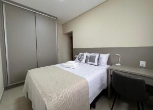 a bedroom with a bed and a desk with a chair at Studio Premium Araxá - Conforto, Localização e Comodidade in Araxá