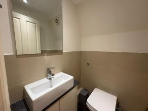 a bathroom with a sink and a toilet and a mirror at The Orderly By Estatesmen in London