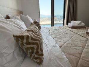 a bedroom with a bed with white pillows and a window at Sunrise Village Aptera Private Pool Villa in Beritianá +45 photos