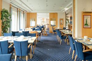 a restaurant with wooden tables and blue chairs at Strandhotel Seestern in Baabe