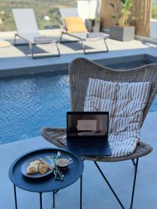 a laptop sitting on a chair with a plate of food at Sunrise Village Aptera Private Pool Villa in Beritianá
