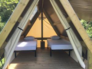 two beds in a pitched room with a tent at Camping Calme et Nature in Castellane