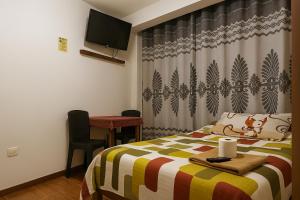 a bedroom with a bed and a desk and a television at hostal kactus in Caraz