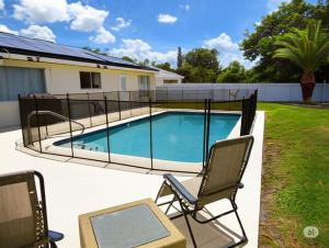 a swimming pool with two chairs next to a house at Splash Oasis, 4BR, 2BA Heated Pool, BBQ in Port Saint Lucie