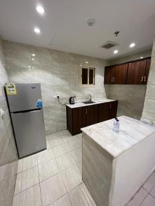 a kitchen with a refrigerator and a sink at AL-Diyafh Hotel in Az Zāhir