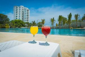 two wine glasses sitting on a table next to a pool at Elemnt Rentals in Santa Marta
