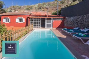 a swimming pool in front of a red building with chairs at Casa Lolita, Valsequillo in Islas Canarias